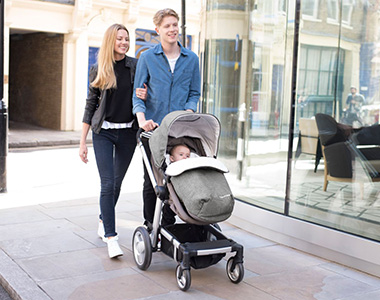 parents taking their baby out for a walk in a mothercare pushchair