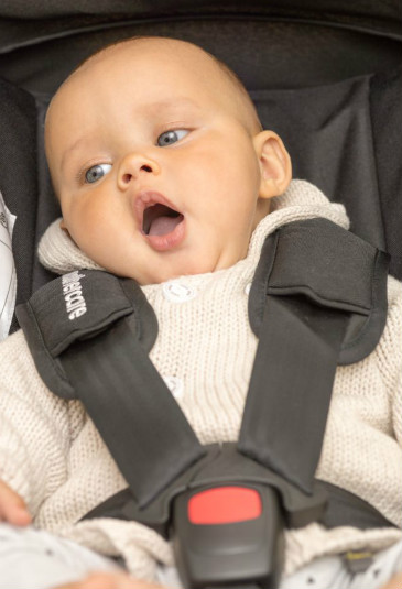 yawning baby in an i-size car seat